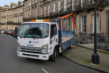 White truck with orange crane on a city street with historic buildings.
