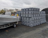 Stack of gray plastic containers next to a boat on a trailer